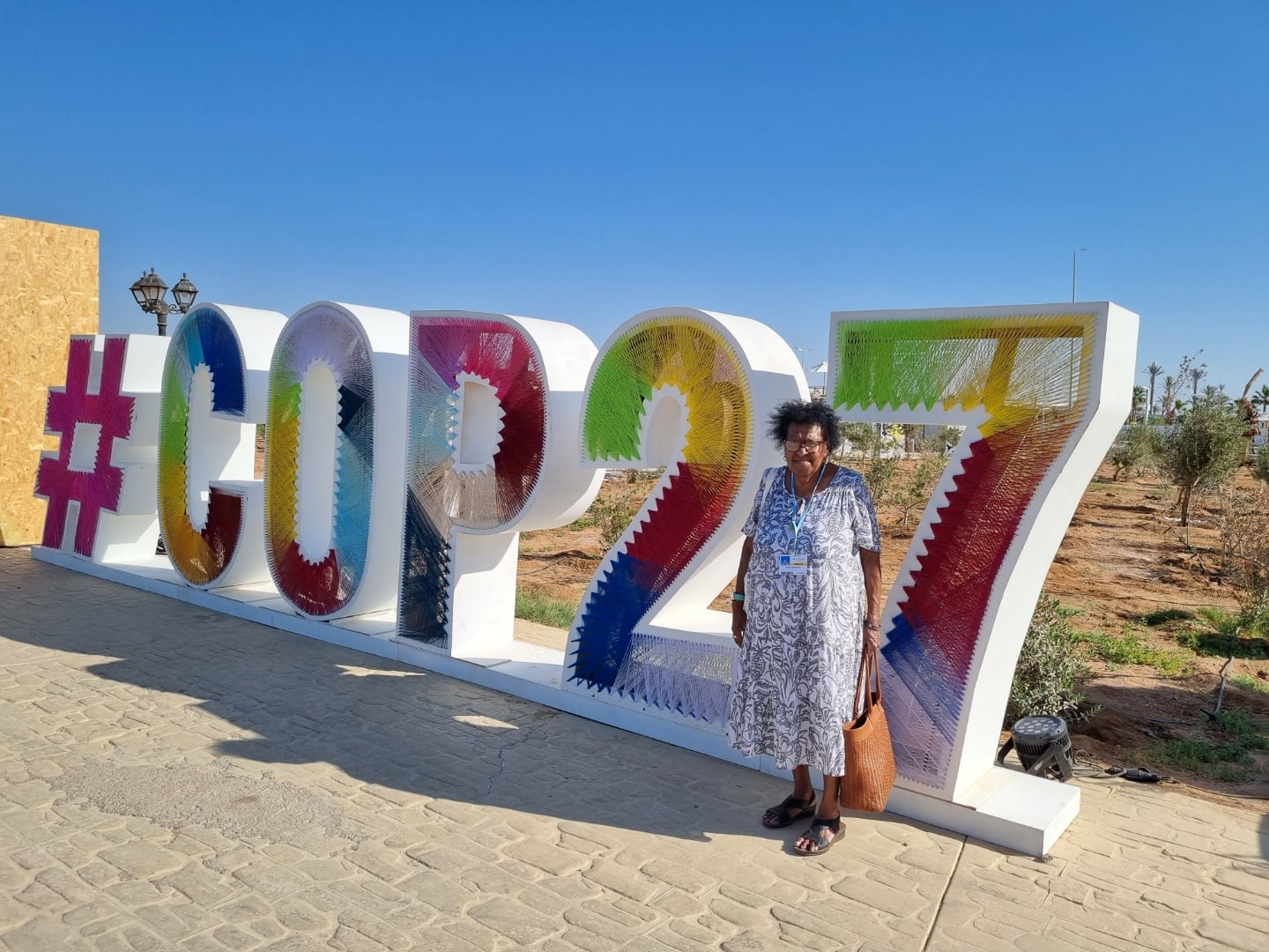 Aunty Rose Elu standing by the Cop27 sign in Egypt - Regenerative Story