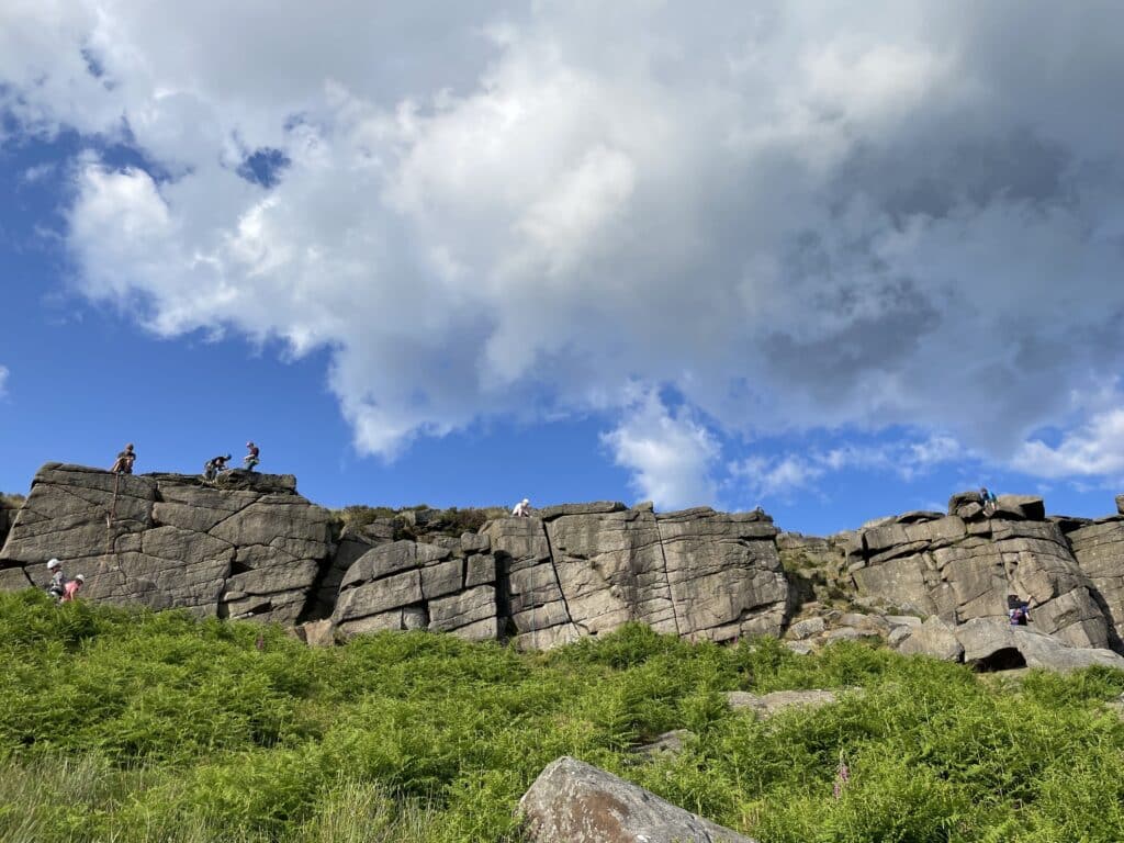 A picture taken by Claire on her visit to the Peak District. The grassy banks and blue but cloud spotted sky are struck either side of the stacked rocks.